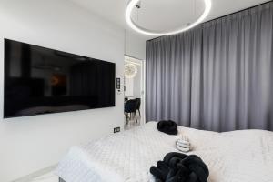 sypialnia z białym łóżkiem i dużym telewizorem w obiekcie Holiday Exclusive w Rewalu