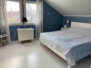 a blue bedroom with a bed and two windows at Hienoa talo porealtaalla lähelllä Helsinkiä ja lentokenttää in Tuusula