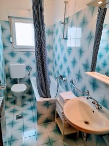 La salle de bains est pourvue de carrelage bleu, d'une baignoire et d'un lavabo. dans l'établissement Apartments Tiho&Marija, à Tribunj