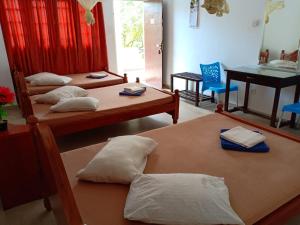 een kamer met drie bedden met kussens en een tafel bij Hotel Senora in Kataragama