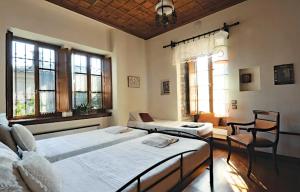 ミリエスにあるMilies Historic Chalet Pelionのベッドルーム1室(ベッド2台、椅子、窓付)