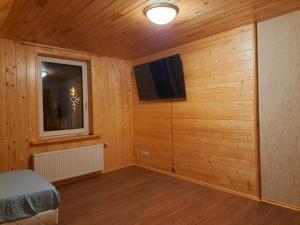 um quarto com paredes de madeira, uma televisão e uma cama em Saules Rats Apartamenti em Madona