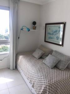 1 dormitorio con cama con almohadas y ventana en DEPARTAMENTO OCEAN DRIVE CON ATARDECER, en Punta del Este