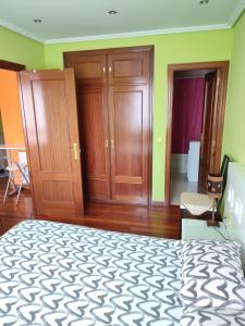 una camera con letto, armadi in legno e sedia di Apartamento con piscinas a Castro-Urdiales