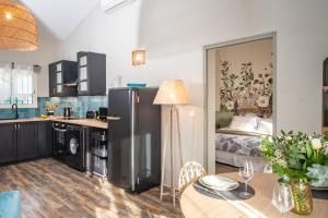uma cozinha com um frigorífico, uma mesa e uma cama em Villa "L'émeraude - Maison d'Hôtes - Jardin et parking privés - Valbonne em Valbonne
