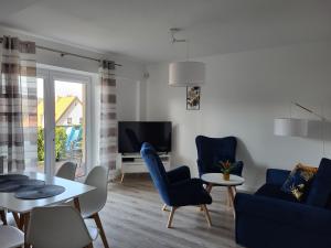 ein Wohnzimmer mit blauen Stühlen, einem Tisch und einem TV in der Unterkunft Apartament z widokiem-Bliżej Zdroju in Polanica-Zdrój