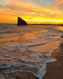a sunset on the beach with a rock in the water at Casa Vacanza Nonna Maria in Torre Pali 