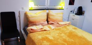 Schlafzimmer mit einem Bett mit gelber Bettwäsche und Kissen in der Unterkunft Klein und fein in Erftstadt
