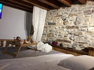 um quarto com uma parede de pedra, uma cama e uma mesa em Casa Charma em Émbonas
