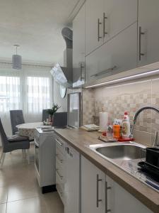 uma cozinha com armários brancos e um lavatório em Apartman Nova Varos em Banja Luka