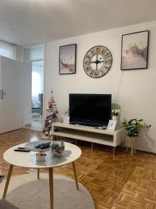 uma sala de estar com televisão e um relógio na parede em Apartman Nova Varos em Banja Luka