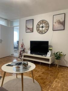 a living room with a tv and a clock on the wall at Apartman Nova Varos in Banja Luka