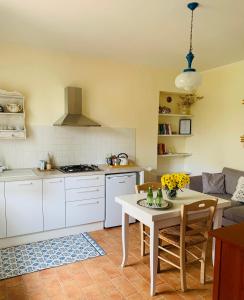 uma cozinha com uma mesa branca, uma mesa e cadeiras em Podere Gradisca em Alberese