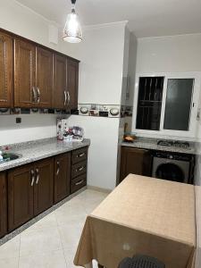 eine Küche mit Holzschränken und einem Tisch darin in der Unterkunft Appartement boulaàyoun de luxe à louer nador 3 in Nador