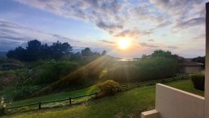 a sunset over a yard with a fence and trees at I 6 Goose Valley! Golf and more in Plettenberg Bay