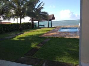 a backyard with a swimming pool and palm trees and the ocean at Casa Beira Mar Serrambi in Porto De Galinhas
