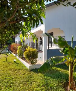 una casa blanca con un patio con árboles y césped en flowerhouse Sukuta Gambia, en Sukuta