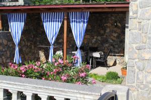 uma varanda com cortinas e flores azuis e uma mesa em Kuca za odmor_Danica em Sveti Juraj