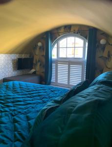 a bedroom with a blue bed with a window at The Pigsty in Braunton in Braunton