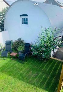 three chairs and a table in a yard with an arbor at The Pigsty in Braunton in Braunton