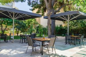 a patio with tables and chairs under umbrellas at Acropol Hotel in Athens