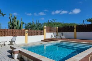 a swimming pool in a backyard with a wooden fence at Private Peaceful Paradise on One Happy Island in Oranjestad