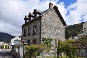 une ancienne maison en pierre avec une clôture devant elle dans l'établissement Petit duplex de charme sous les toits du Mont-Dore, à Le Mont-Dore