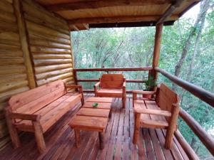 un porche de una cabaña de madera con bancos y mesas en Cabaña La Isla II en 