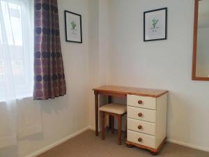 a desk with a chair and a dresser next to a window at Owl Haven: Comfortable central 3 bedroom house, with an enclosed garden. in Bicester