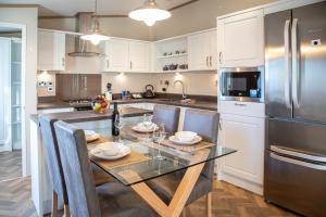 a kitchen with a dining table and a stainless steel refrigerator at Stewarts Resort Lodge 27 in St. Andrews