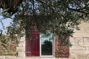 a red window on a building with a tree at CASA DO ESTÁBULO - Vila Garcia - Trancoso 