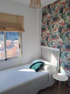 a bedroom with a bed and a window with floral wallpaper at La Casica in Chulilla