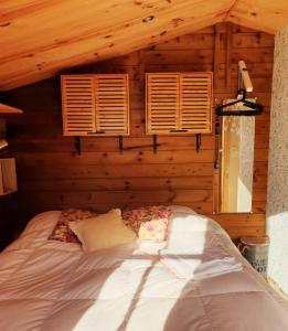 Ce lit se trouve dans une chambre en bois dotée de 2 fenêtres. dans l'établissement Le Chalet du Clos Giot, à Saint-Vaast-la-Hougue