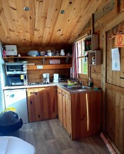a kitchen with wooden cabinets and a sink in a cabin at Le Chalet du Clos Giot in Saint-Vaast-la-Hougue