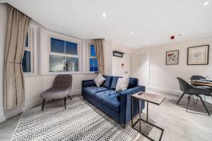 een woonkamer met een blauwe bank en een tafel bij Trendy 2 bedroom 2 bathroom apartment minutes from seafront in St Leonard's Hastings in St. Leonards