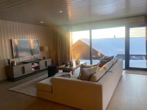 ein Wohnzimmer mit einem weißen Sofa und einem TV in der Unterkunft Appartment Norefjell ski in/ski out in Noresund