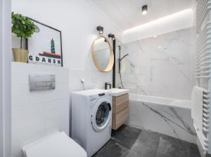 een witte badkamer met een wasmachine bij Apartament na Rybakach in Gdańsk