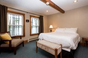 a bedroom with a bed and a chair and two windows at The Lodge at Pleasant Point in Lovell