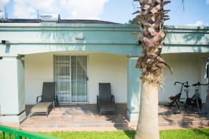 a house with two chairs and a palm tree at Haithoms Guesthouse in Gaborone