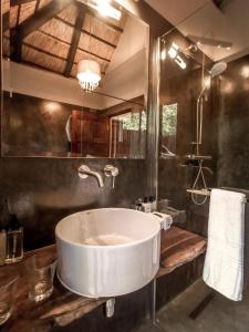 a bathroom with a large white sink and a mirror at Kruger Eden Lodge in Marloth Park
