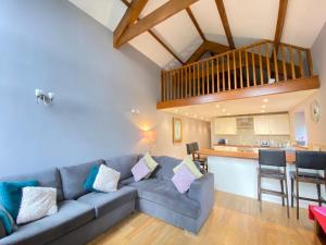 a living room with a blue couch and a kitchen at Heronston Barn Cottage in Bridgend