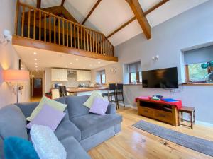 a living room with a couch and a tv at Heronston Barn Cottage in Bridgend