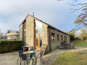 a stone house with a table and chairs in front of it at Heronston Barn Cottage in Bridgend