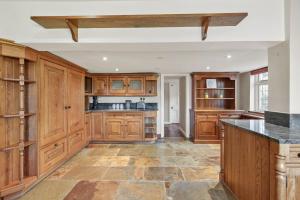 a kitchen with wooden cabinets and a large island at 6 Bed Countryside Mansion With Tennis Court & Swimming Pool with Parking in East Horsley