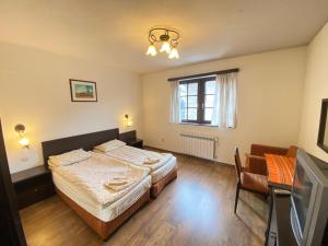 Schlafzimmer mit einem Bett, einem Schreibtisch und einem TV in der Unterkunft House Trivia in Bansko