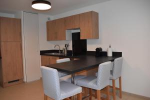 kuchnia z czarnym stołem i białymi krzesłami w obiekcie Le Saint Pierre en Baie Appt 3-4 pers parking privé w mieście Saint-Valéry-sur-Somme