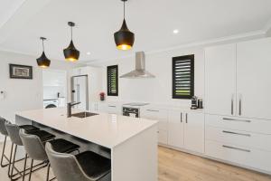 a kitchen with white cabinets and a large island with chairs at Pride of Pinot - Martinborough Holiday Home in Martinborough 
