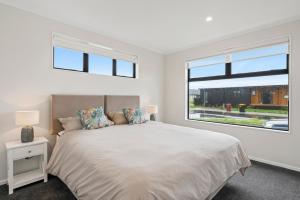 a white bedroom with a large bed and a window at Pride of Pinot - Martinborough Holiday Home in Martinborough  +15 photos