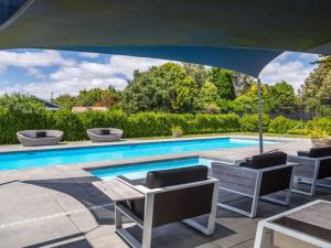 einen Pool mit Stühlen und einem Sonnenschirm in der Unterkunft Pride of Pinot - Martinborough Holiday Home in Martinborough 