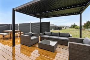 a pergola with couches and a table on a deck at Pride of Pinot - Martinborough Holiday Home in Martinborough 